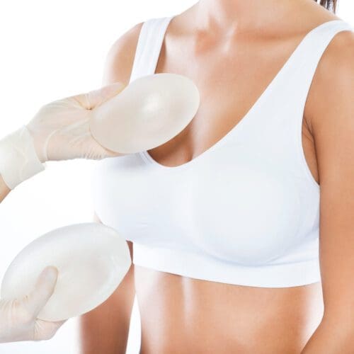 Portrait of female doctor choosing mammary prosthesis with her patient over white background. Breast Augmentation