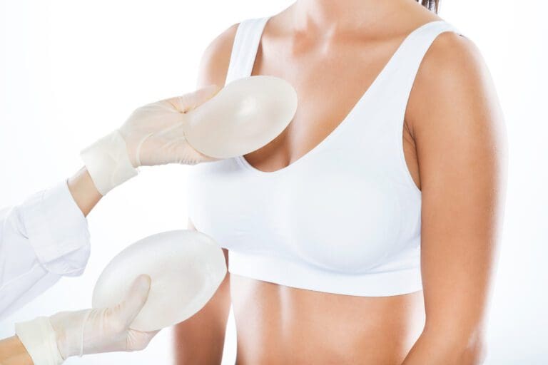 Portrait of female doctor choosing mammary prosthesis with her patient over white background. Breast Augmentation