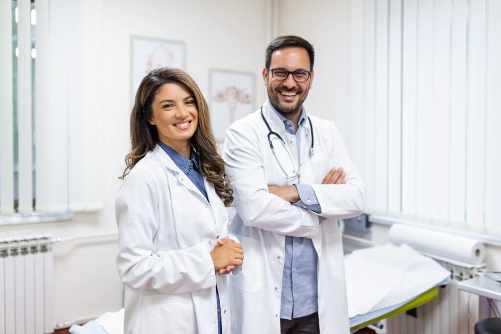 Portrait of smiling young doctors standing together. Portrait Of Medical Staff Inside Modern Hospital Smiling To Camera